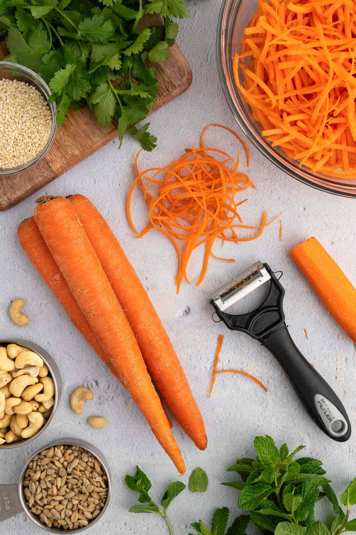 Carrots and carrot shred, surrounded by other prepped ingredients.