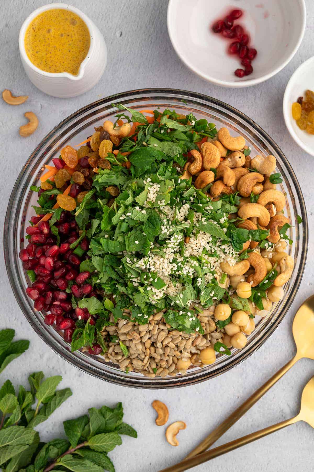 A bowl of greens, cashews, pomegranate seeds and sunflower seeds.