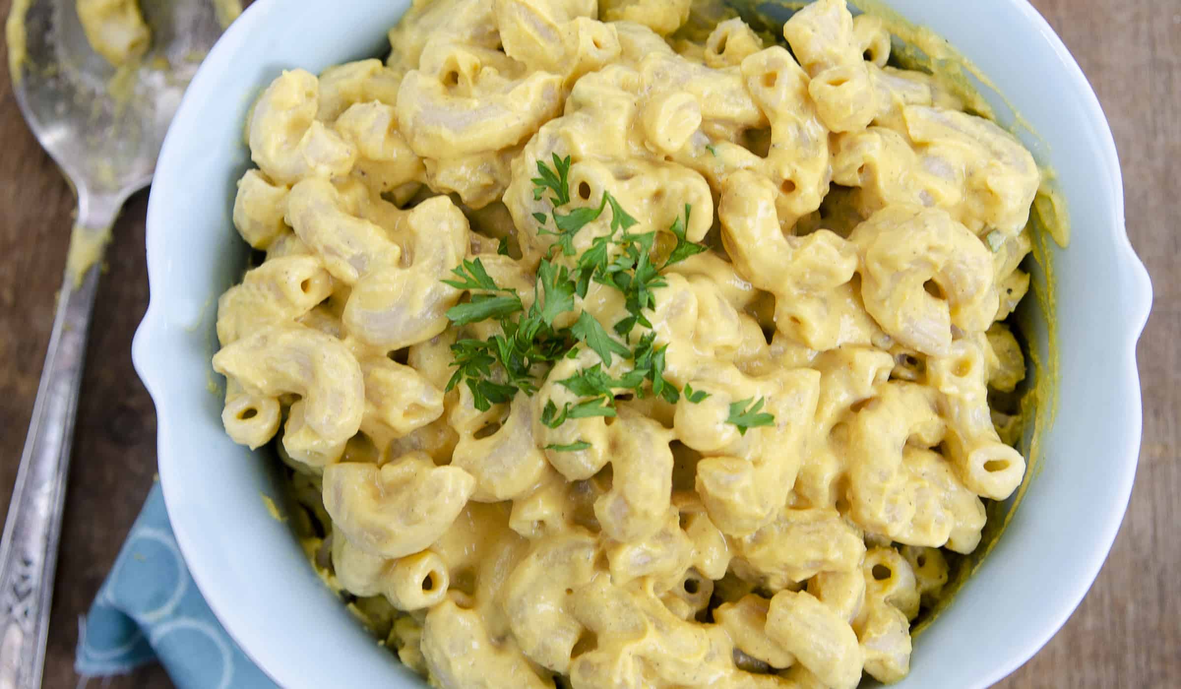 Bowl of vegan mac and cheese without cashews, topped with chopped parsley.