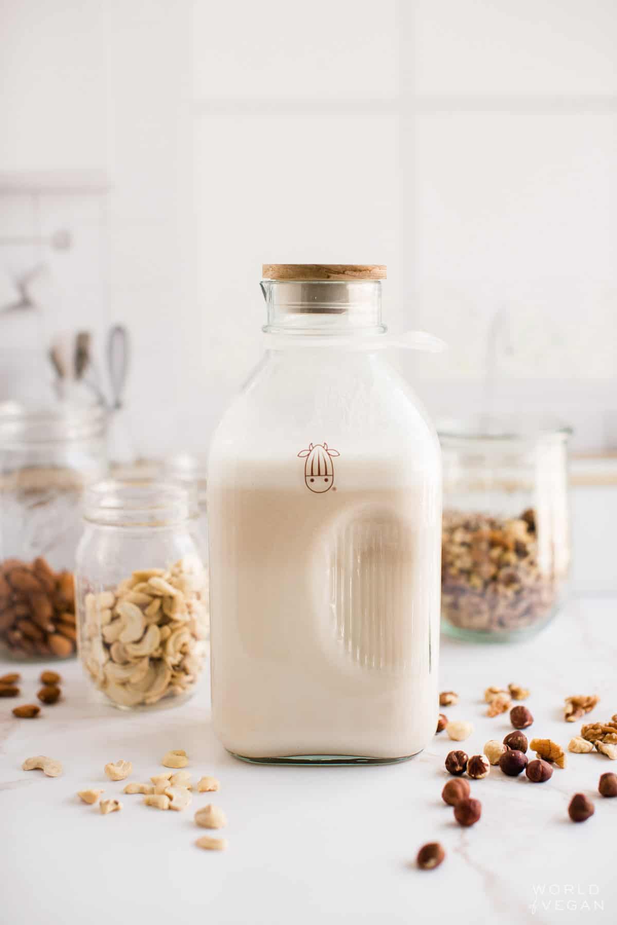 Almond cow milk just filled with protein packed nut milk on a table surrounded by cashews and almonds. 