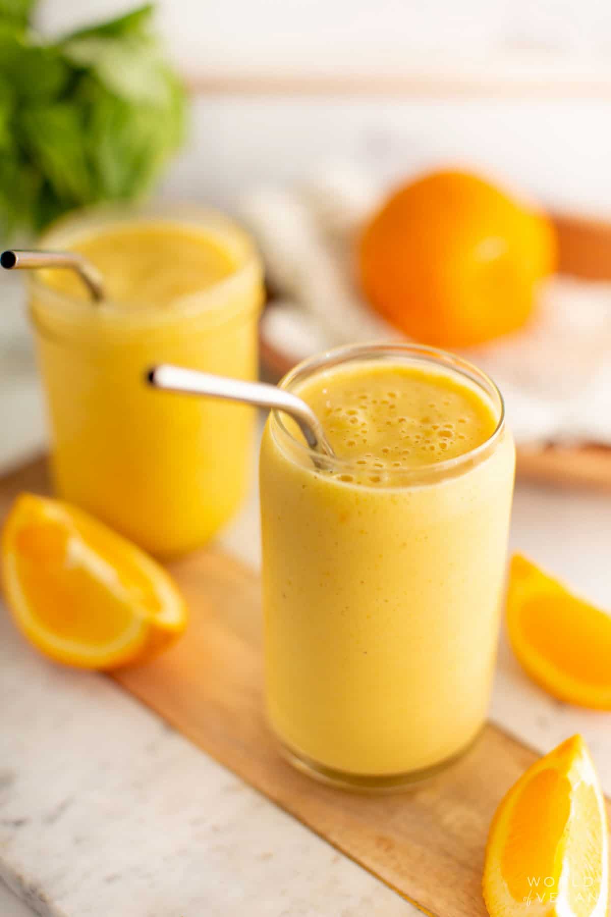 An angled shot of an orange juice smoothie in a glass. 