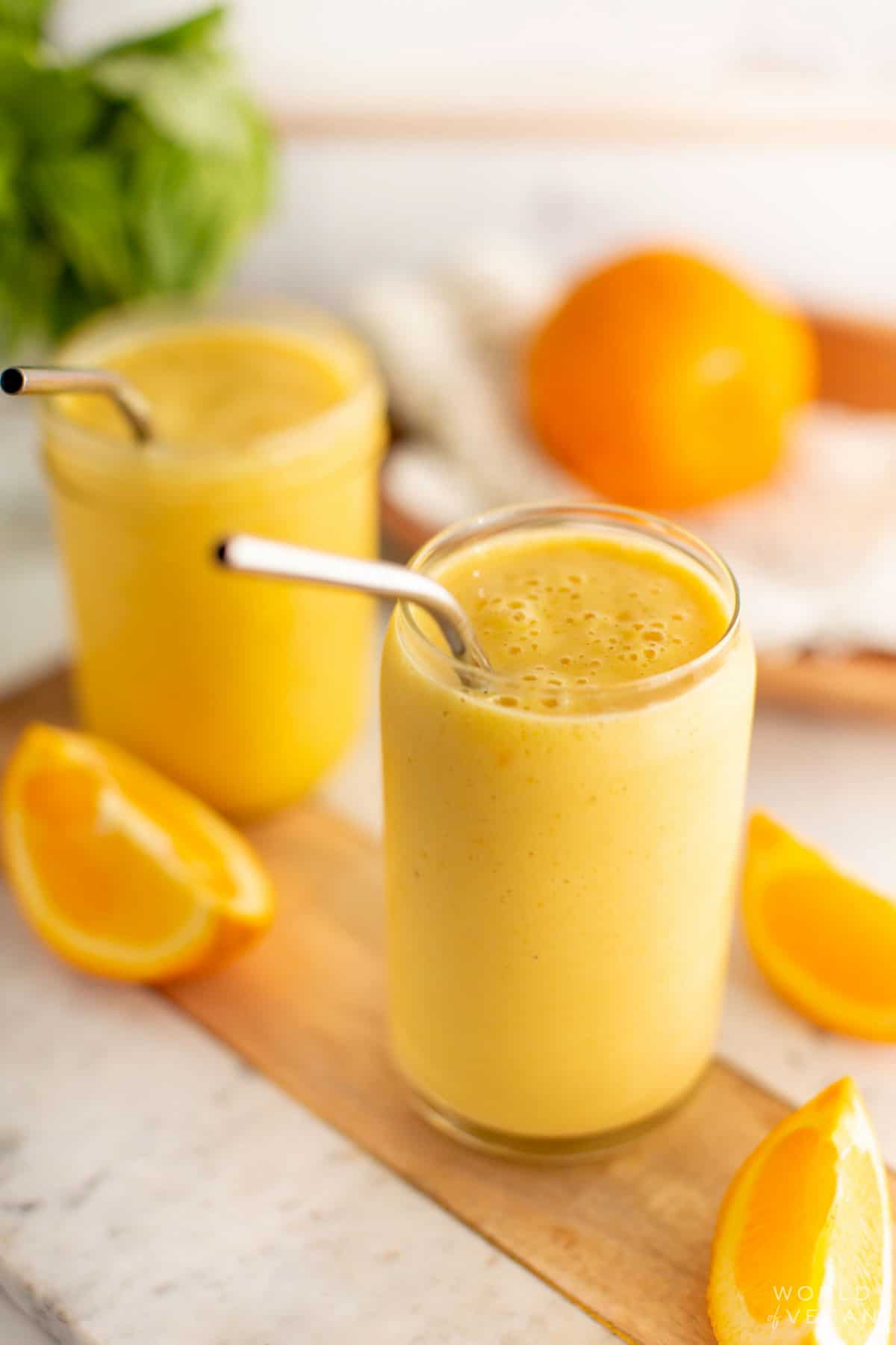 An angled shot of an orange juice smoothie in a glass. 