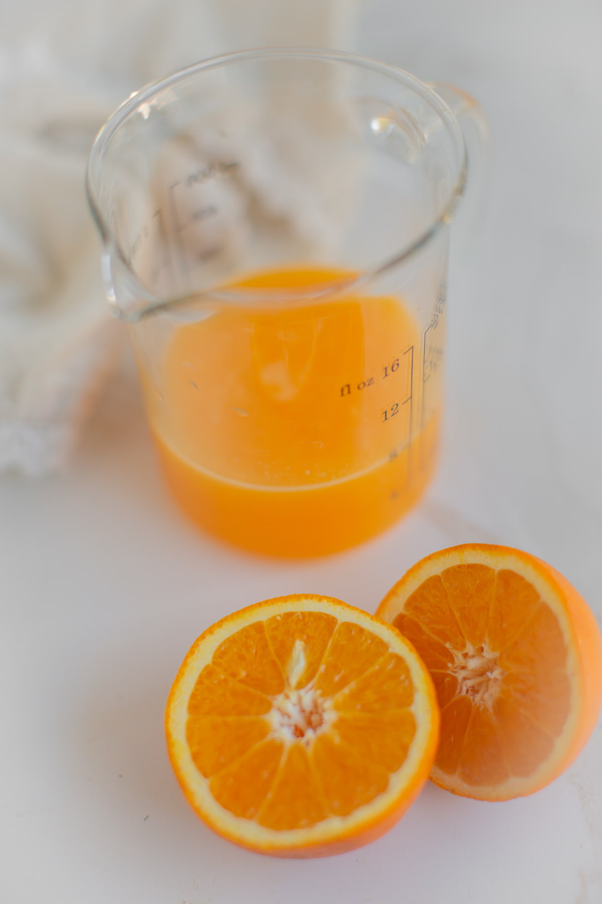 An orange sliced in half next to a pitcher of fresh orange juice.