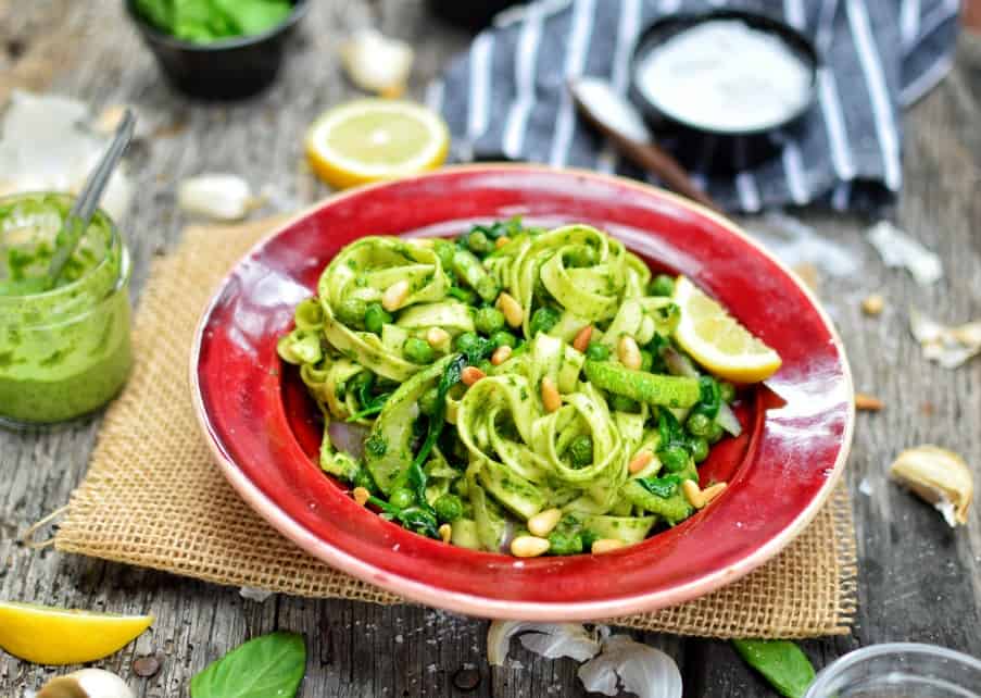 Vegan pesto sauce mixed into linguine pasta with vegetables on a plate.