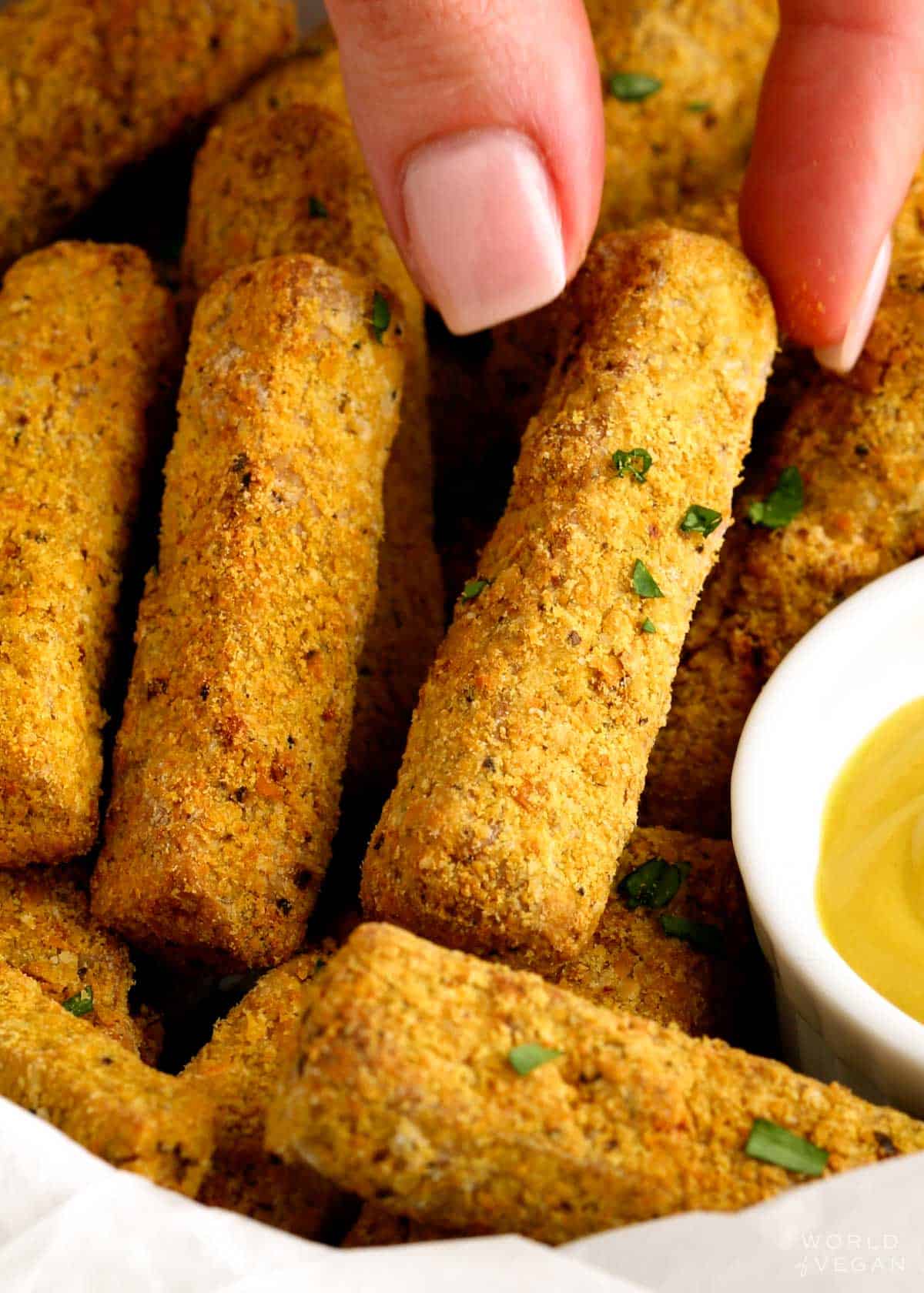 Picking up a crusted tofu fry from a basket of fries. 