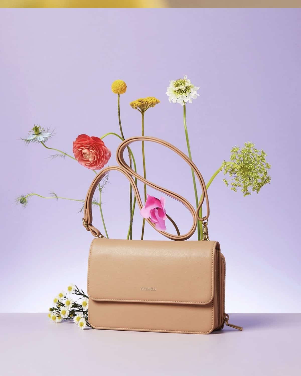 Camel tan small vegan purse from Pixie Mood surrounded by colorful wildflowers. 