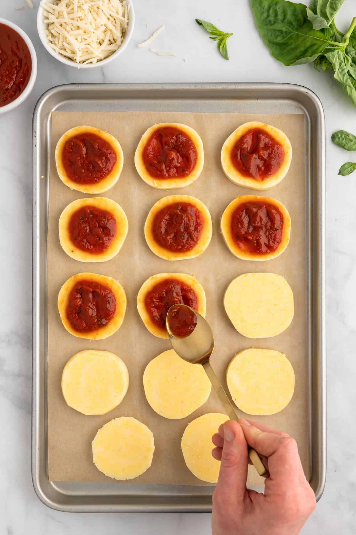 Sauce being spooned over polenta pizza bites.