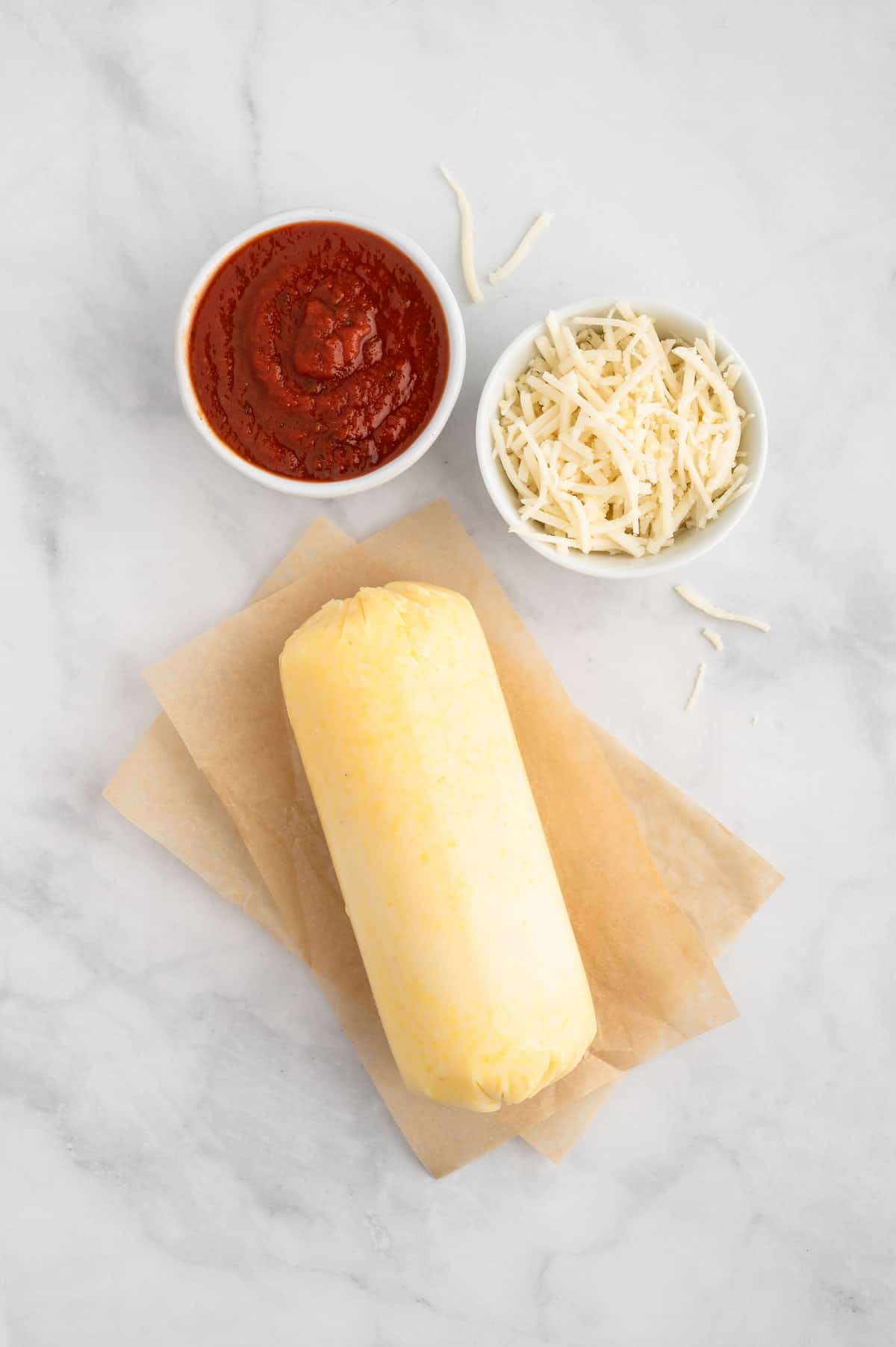 A top-down shot of polenta, sauce, and vegan cheese shreds.