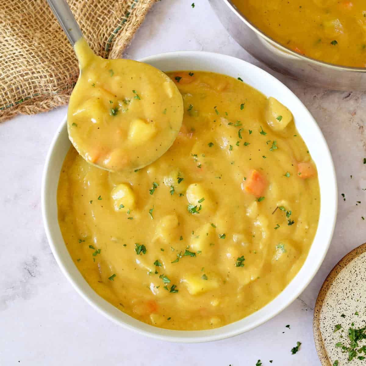 Large bowl of potato soup with a ladle.