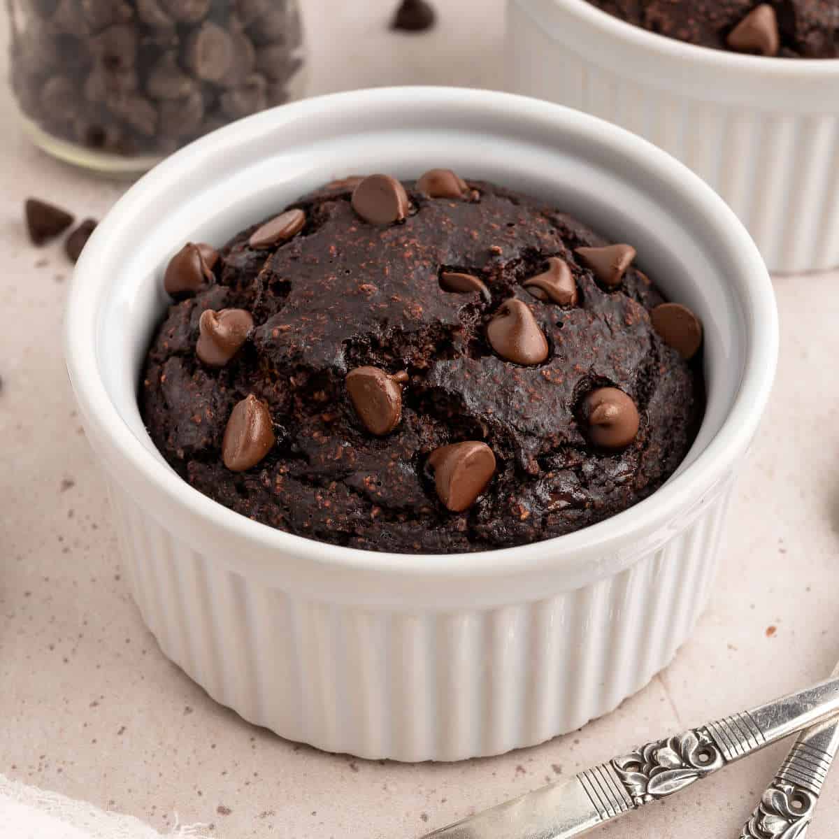 Chocolate protein mug cake in a ramekin topped with chocolate chips.