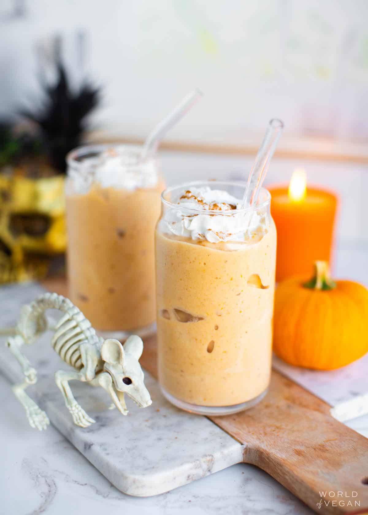 Pumpkin pie milkshakes in glasses, next to Halloween and autumn decorations.