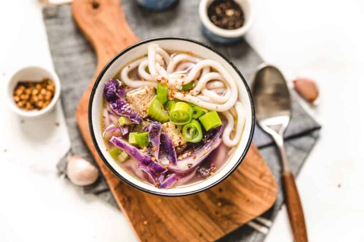Bowl of Purple Udon Noodle Soup Served over a Wooden Board