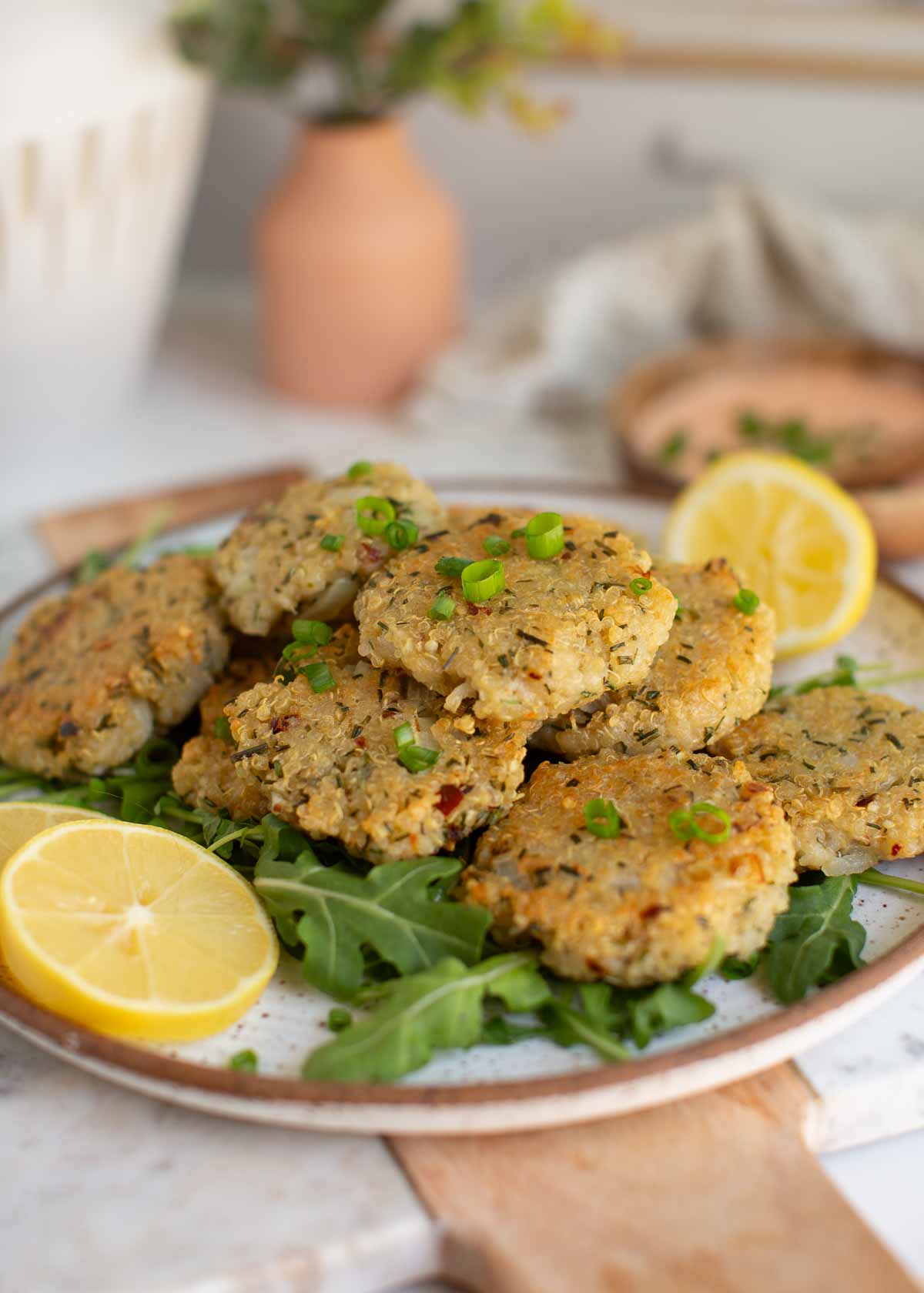 Quinoa bites on a plate of greens, served with sliced lemon.