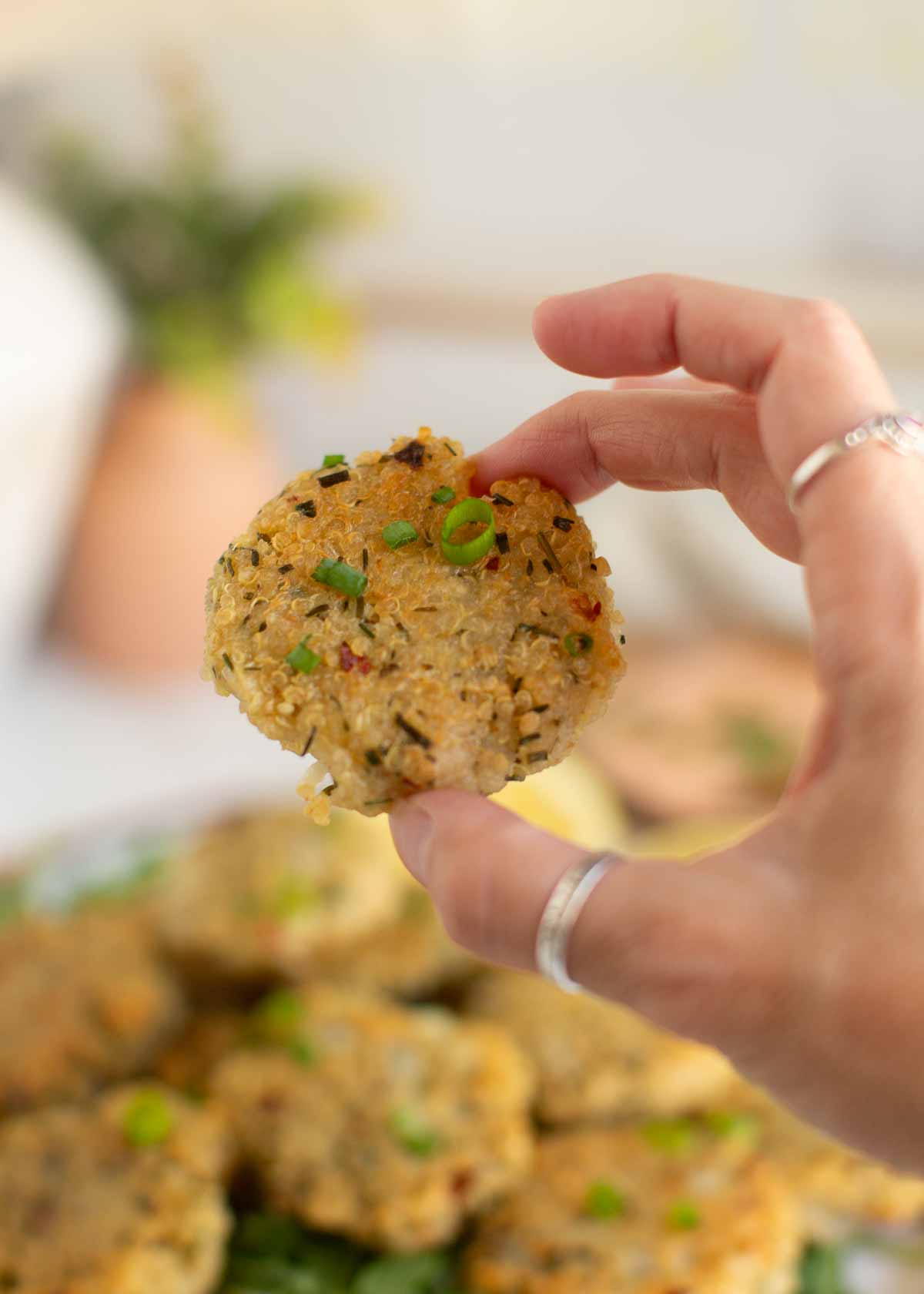 A hand holding up a quinoa nugget.