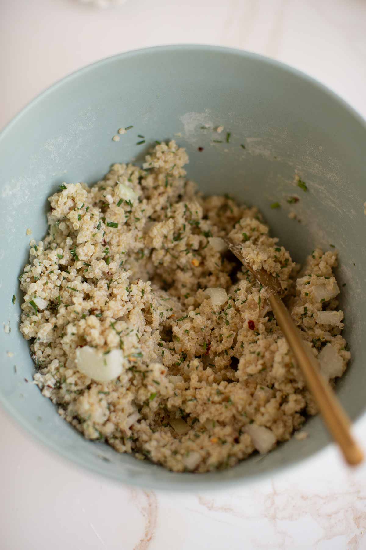 The mixed up quinoa nuggets batter in a mixing bowl with a spoon.