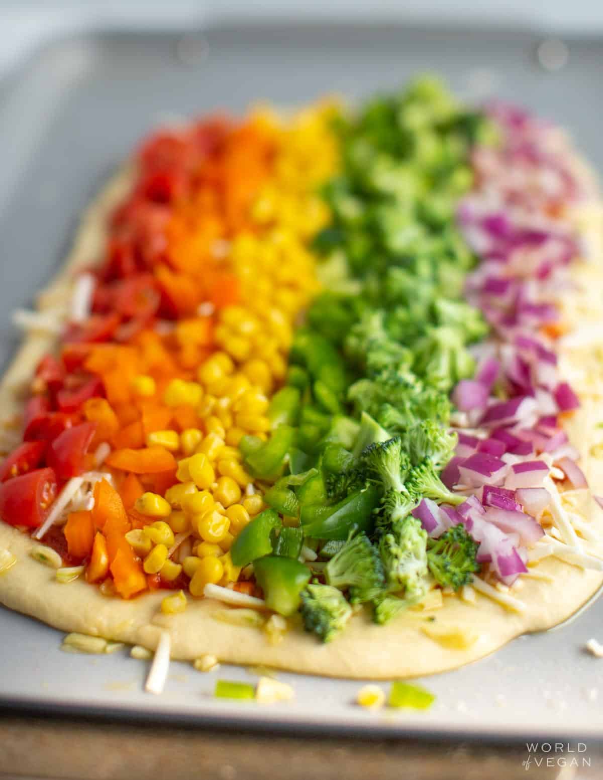 Photo of World of Vegan's rainbow pizza on a baking sheet before baking it in the oven. 