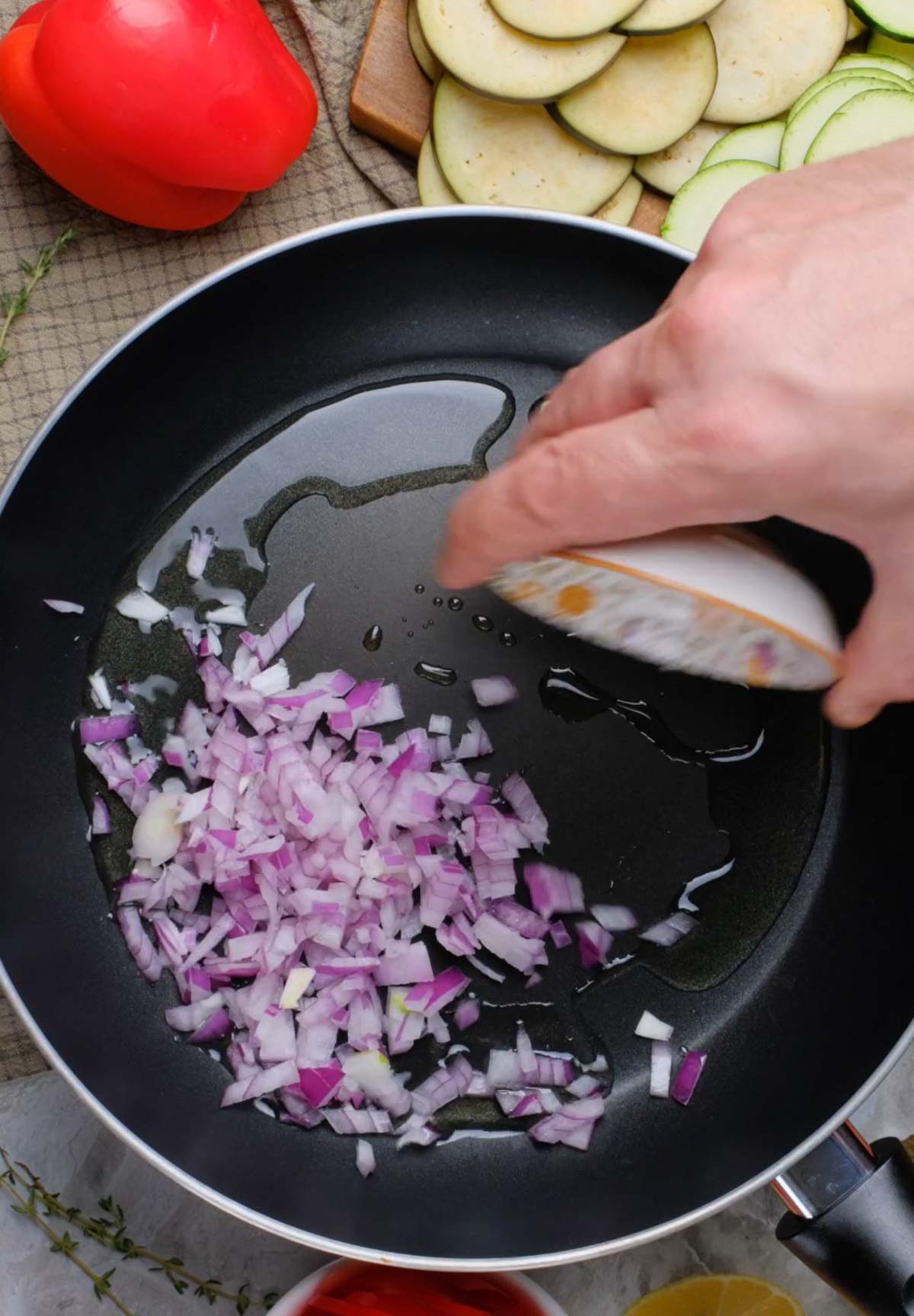 A sauté pan with oil and onions.