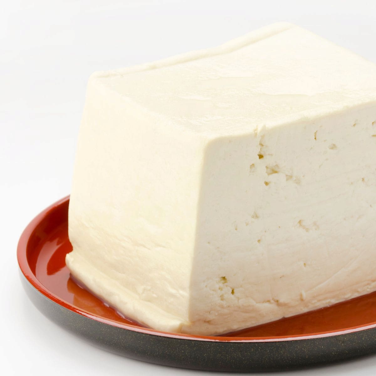 A block of regular tofu, one of the common types of tofu, on a plate.