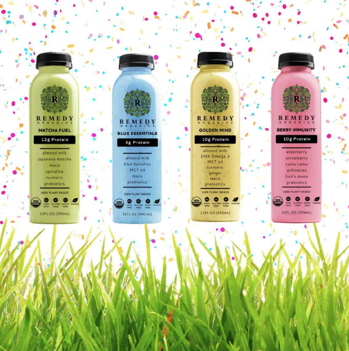 Four bottles of Remedy Organics plant-based protein shakes in light green, light blue, yellow and pink against a background of grass and confetti.