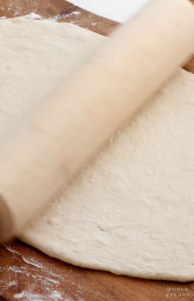 Rolling out vegan pizza dough with a rolling pin.