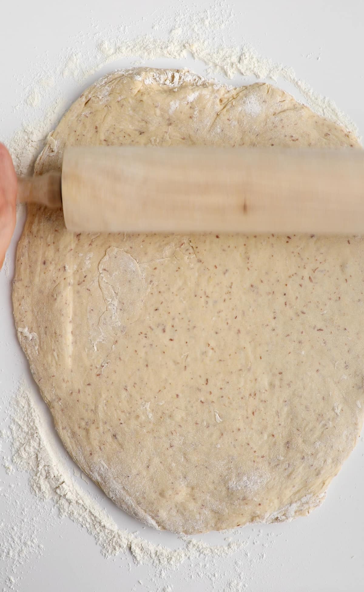 A rolling pin flattening out the vegan cinnamon roll dough.