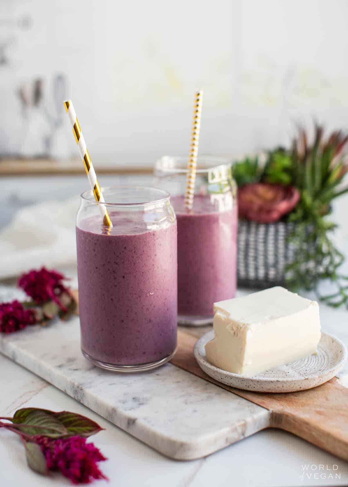 Two glasses filled with a tofu smoothie next to a block of silken tofu.