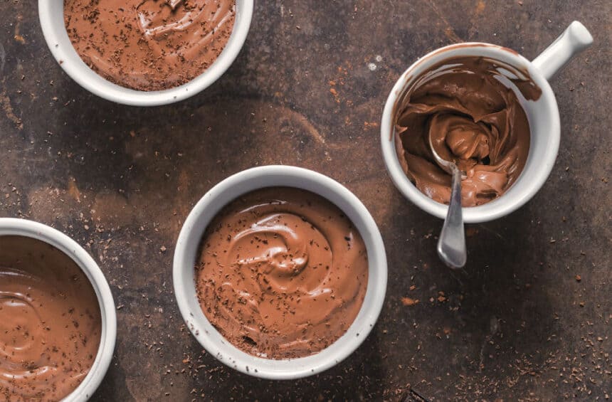 vegan chocolate pudding in multiple mugs against a brown surface