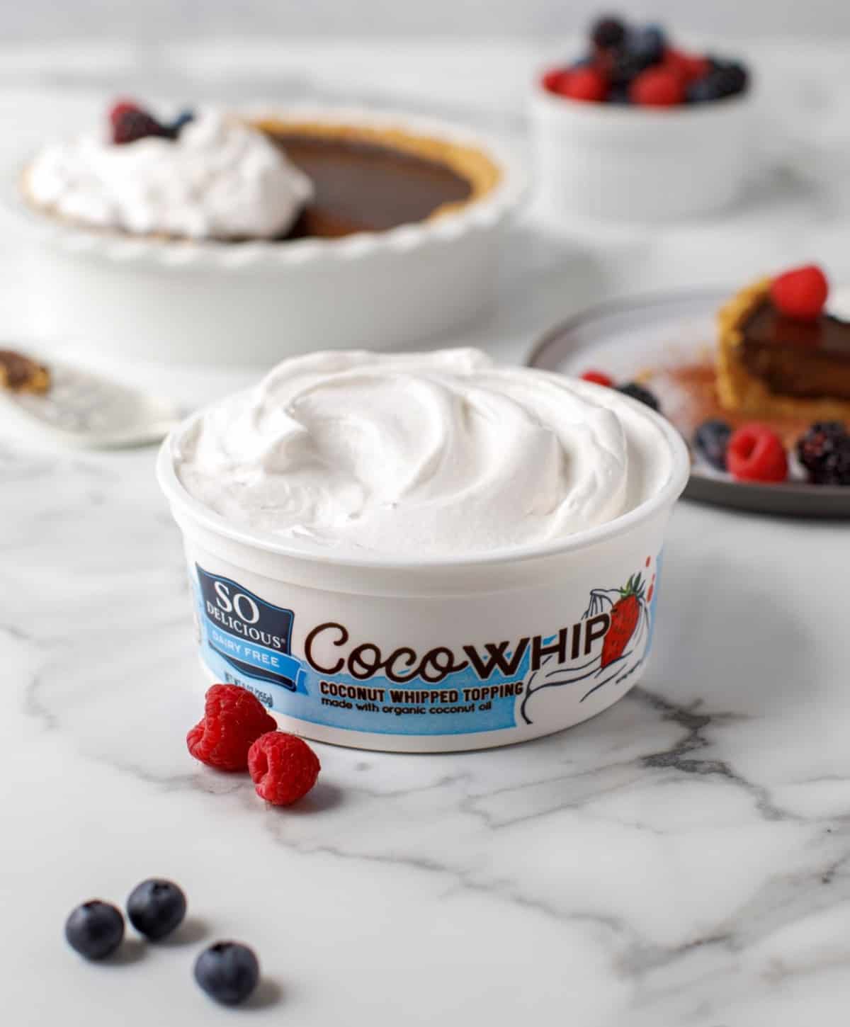 Container of So Delicious Coco Whip dairy-free coconut whipped cream served with pie.