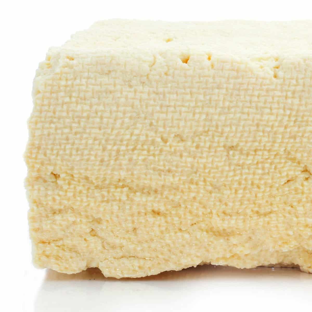 A block of super-firm tofu, one of the common types of tofu, on a white countertop.