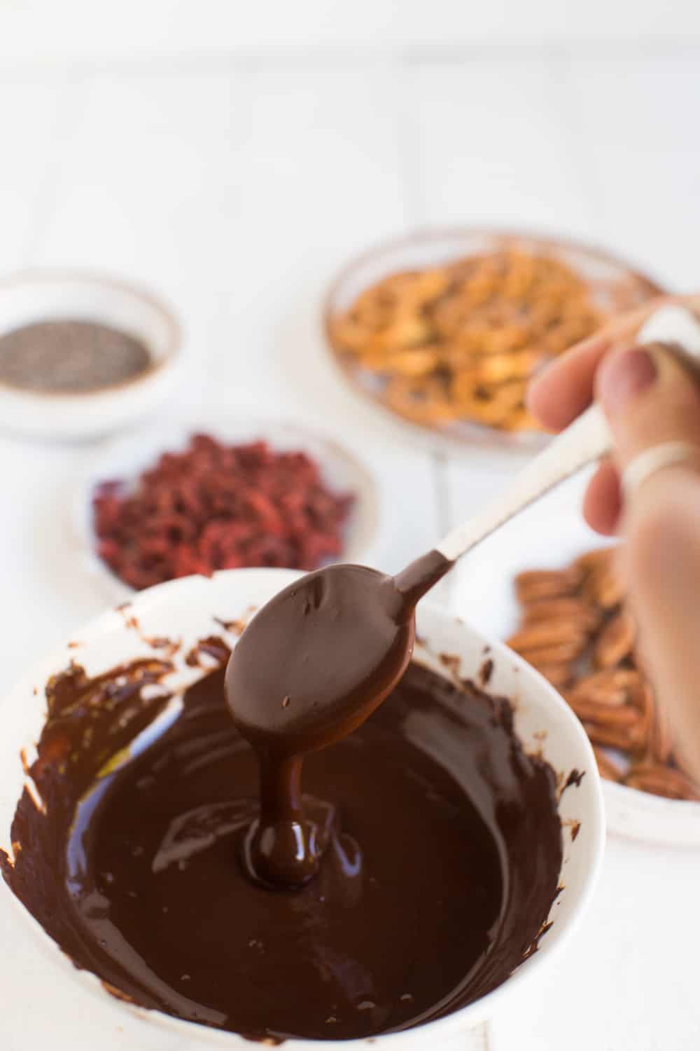 Melted dark chocolate in a bowl dripping from a spoon. 