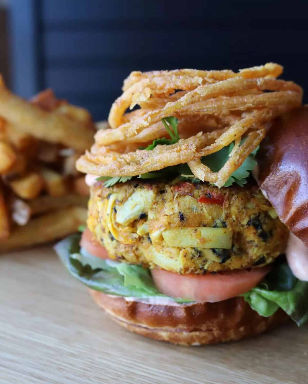 A vegan crab burger topped with onion rings.