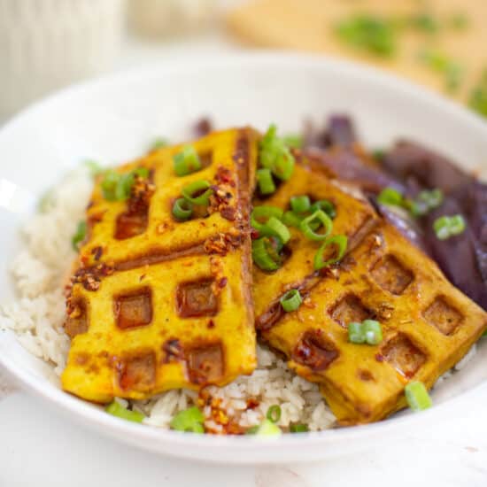 Tofu waffles served on a plate with waffle iron grilled purple onions.