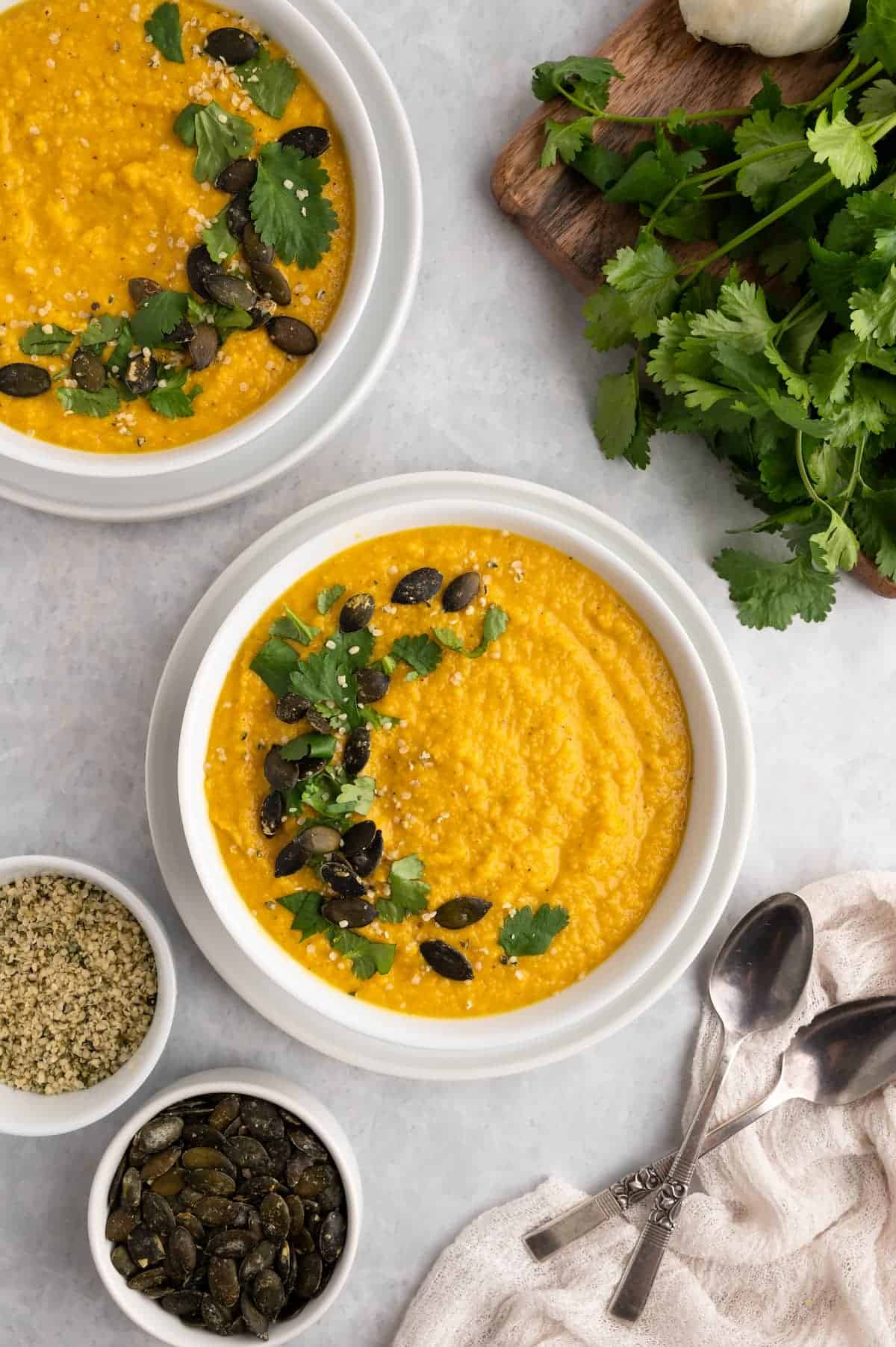 Two bowls of toor dal, garnished in white bowls.