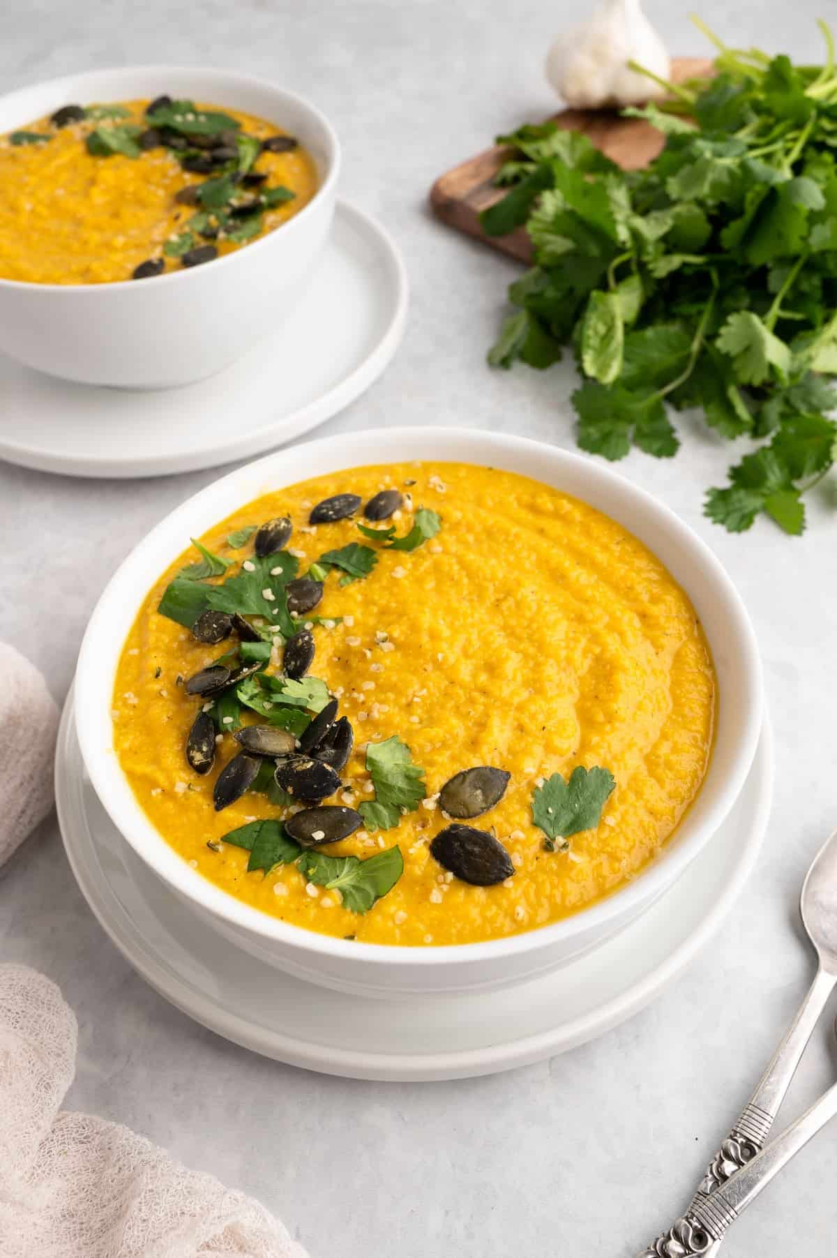 Toor dal in a white bowl with herbs to the side.