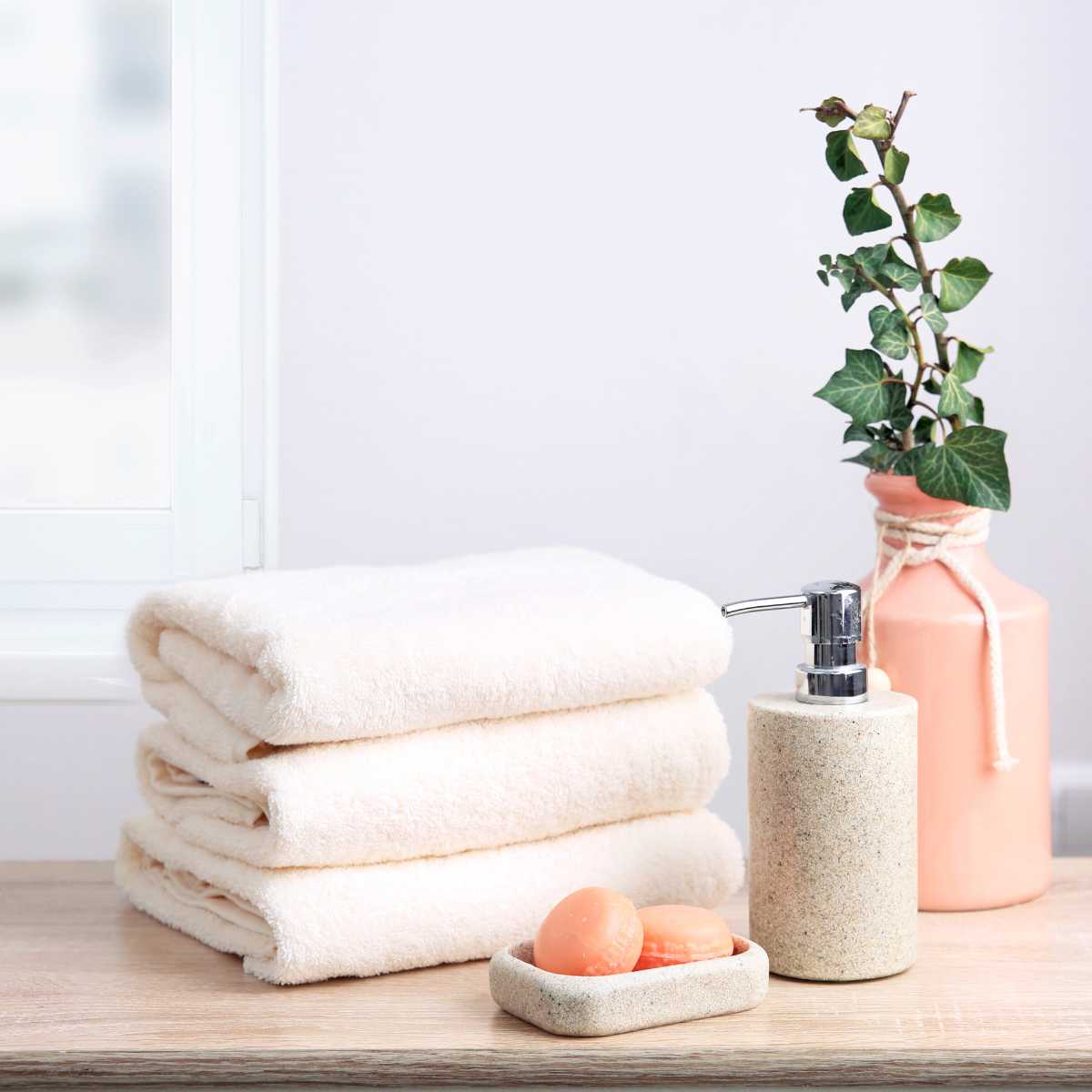 A stack of towels next to vegan wash and soap.