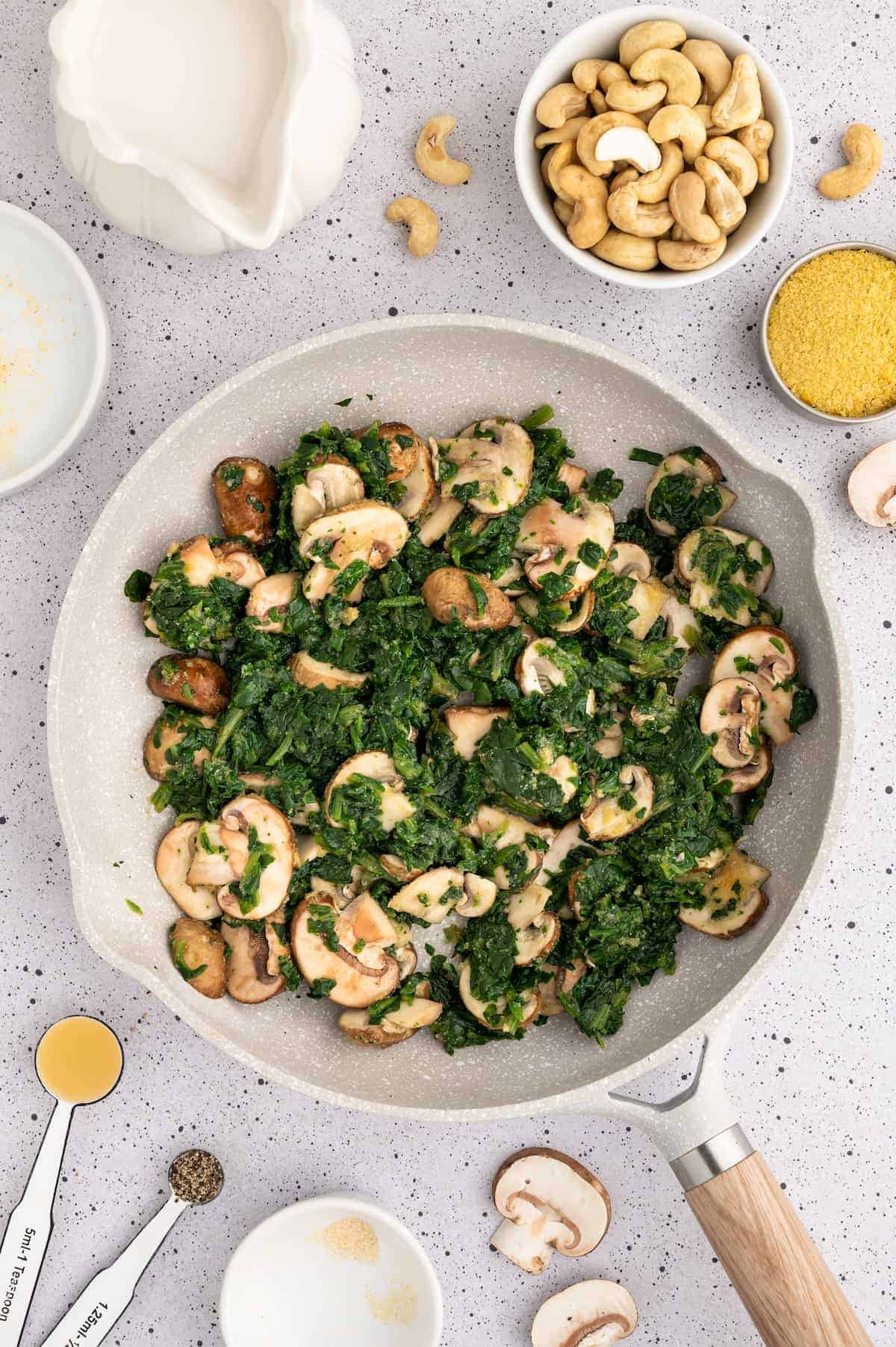 Sautéed mushrooms and spinach in a pan.
