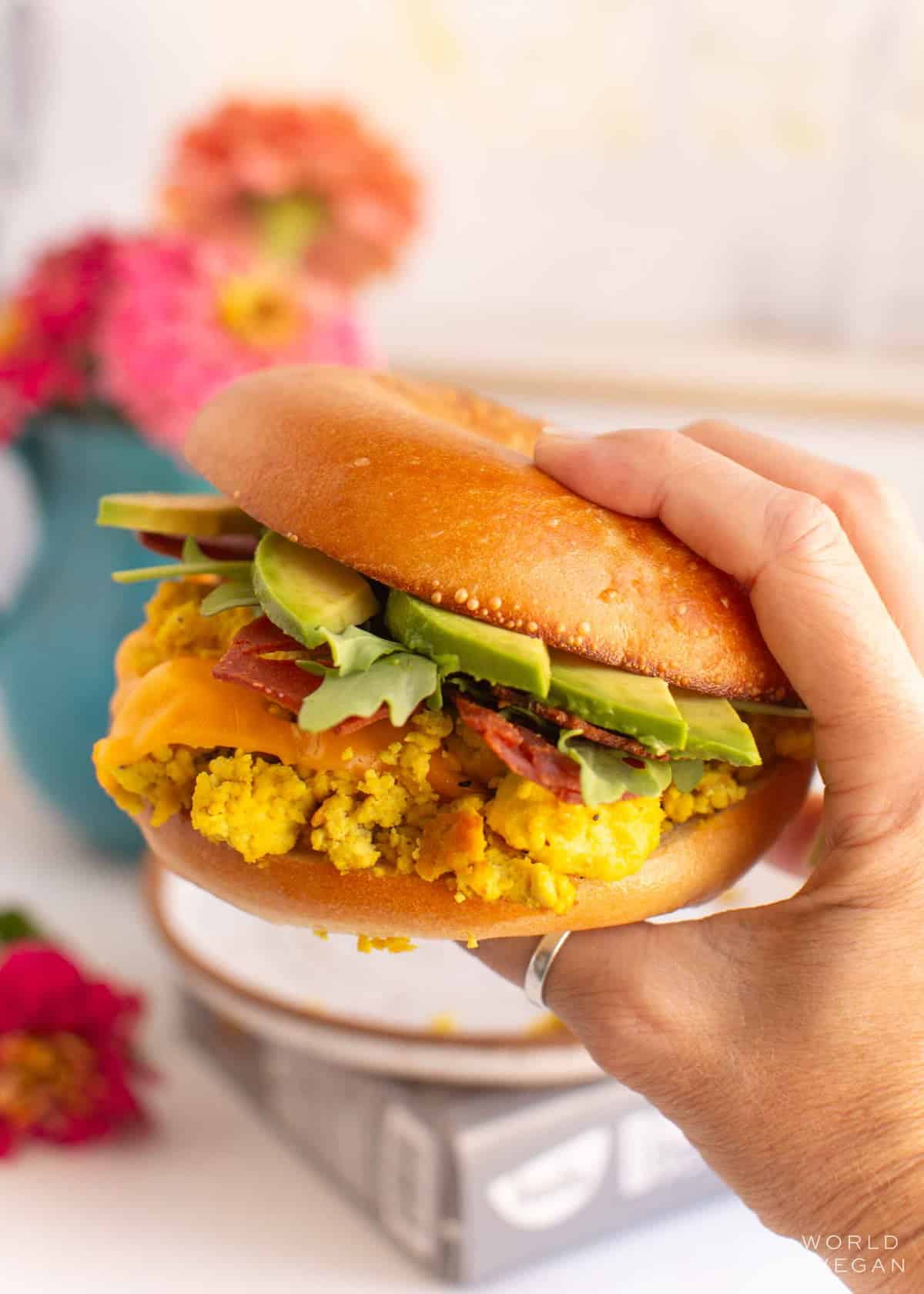 A hand holding a vegan breakfast sandwich.