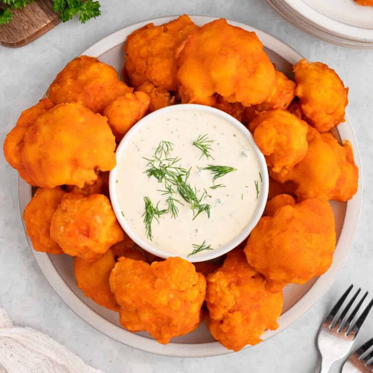 Vegan buffalo cauliflower wings on a plate with vegan ranch dressing.