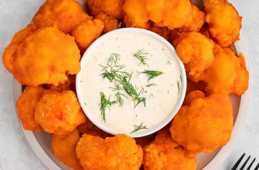 Vegan buffalo cauliflower wings on a plate with vegan ranch dressing.