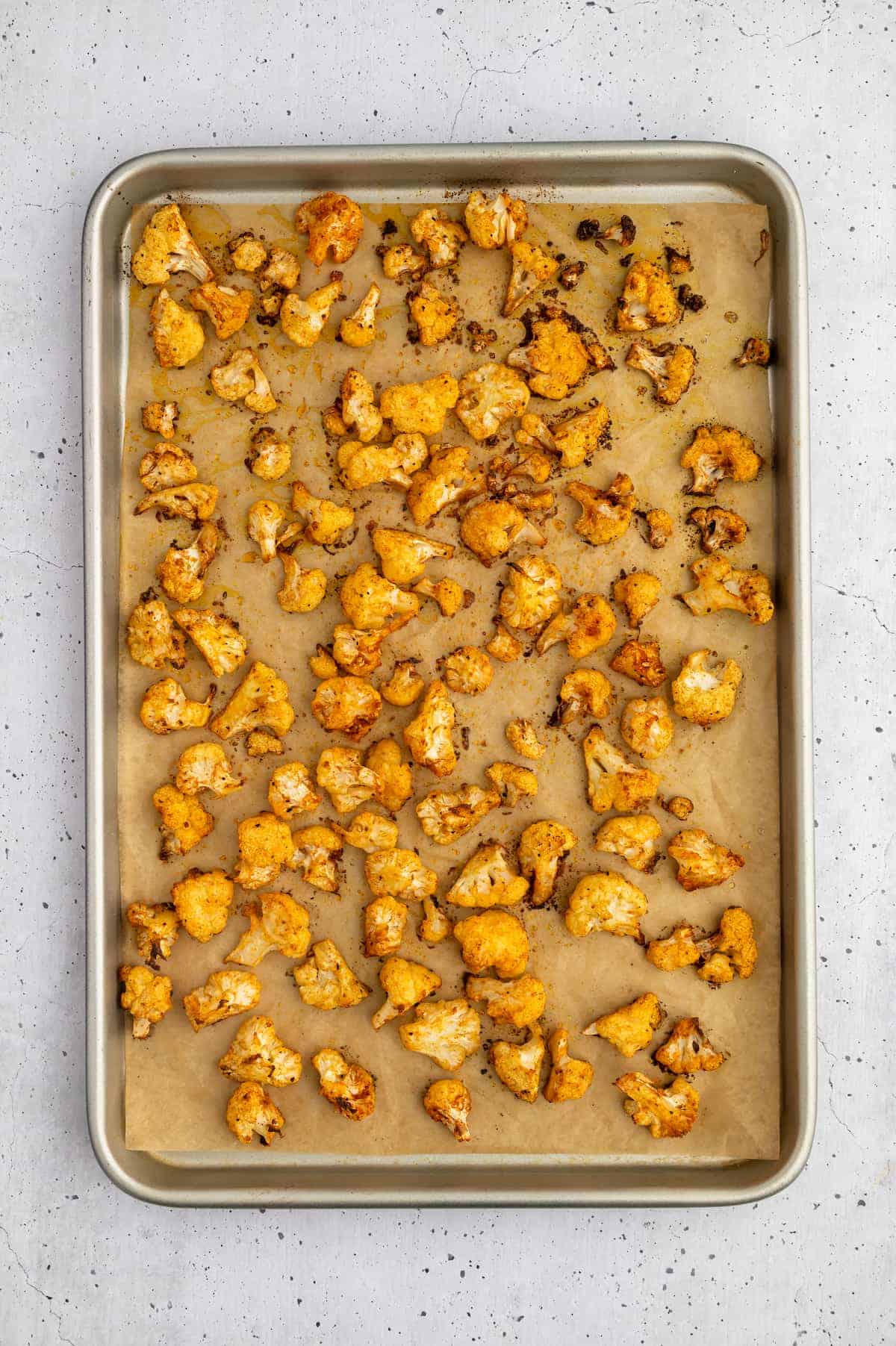 Seasoned and baked cauliflower florets on a baking sheet.