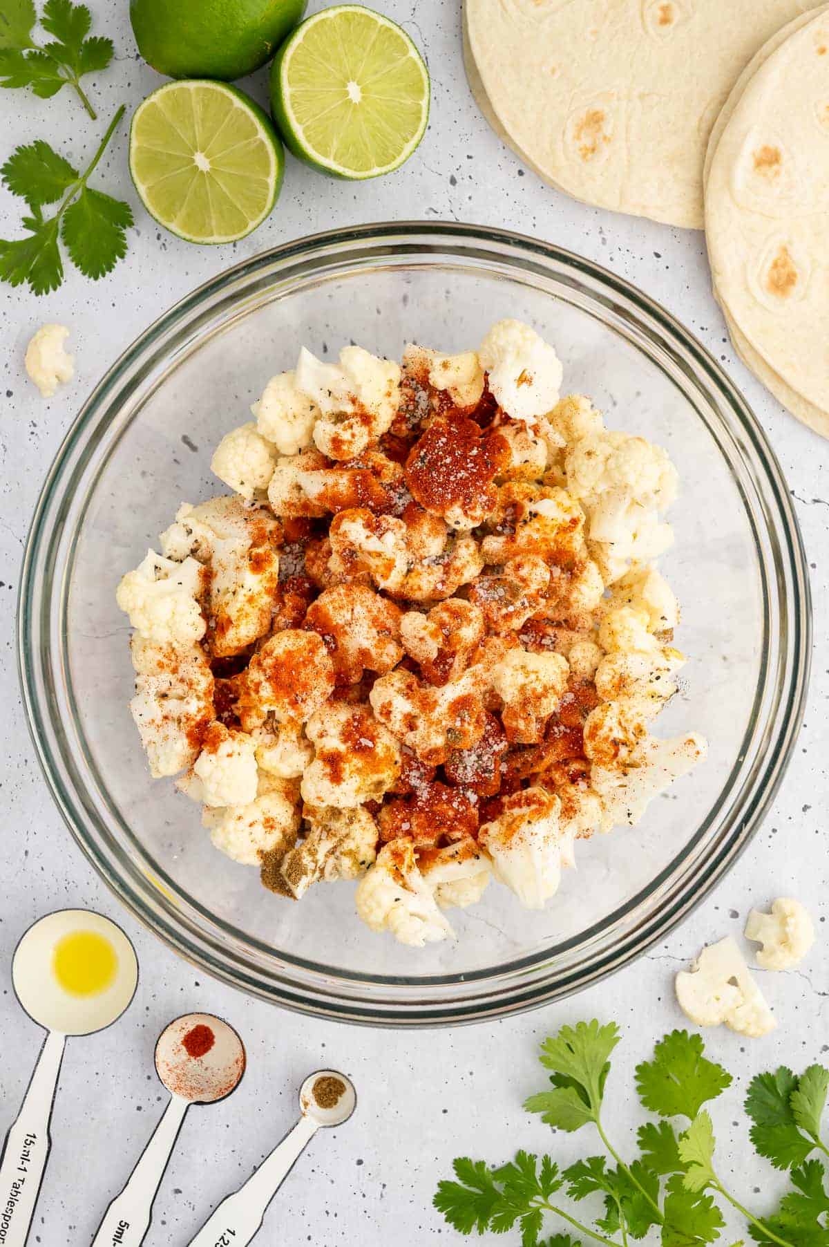 A bowl of cauliflower florets with seasoning.