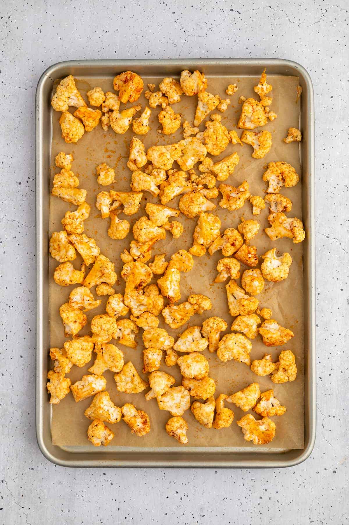 Seasoned cauliflower florets on a baking sheet.