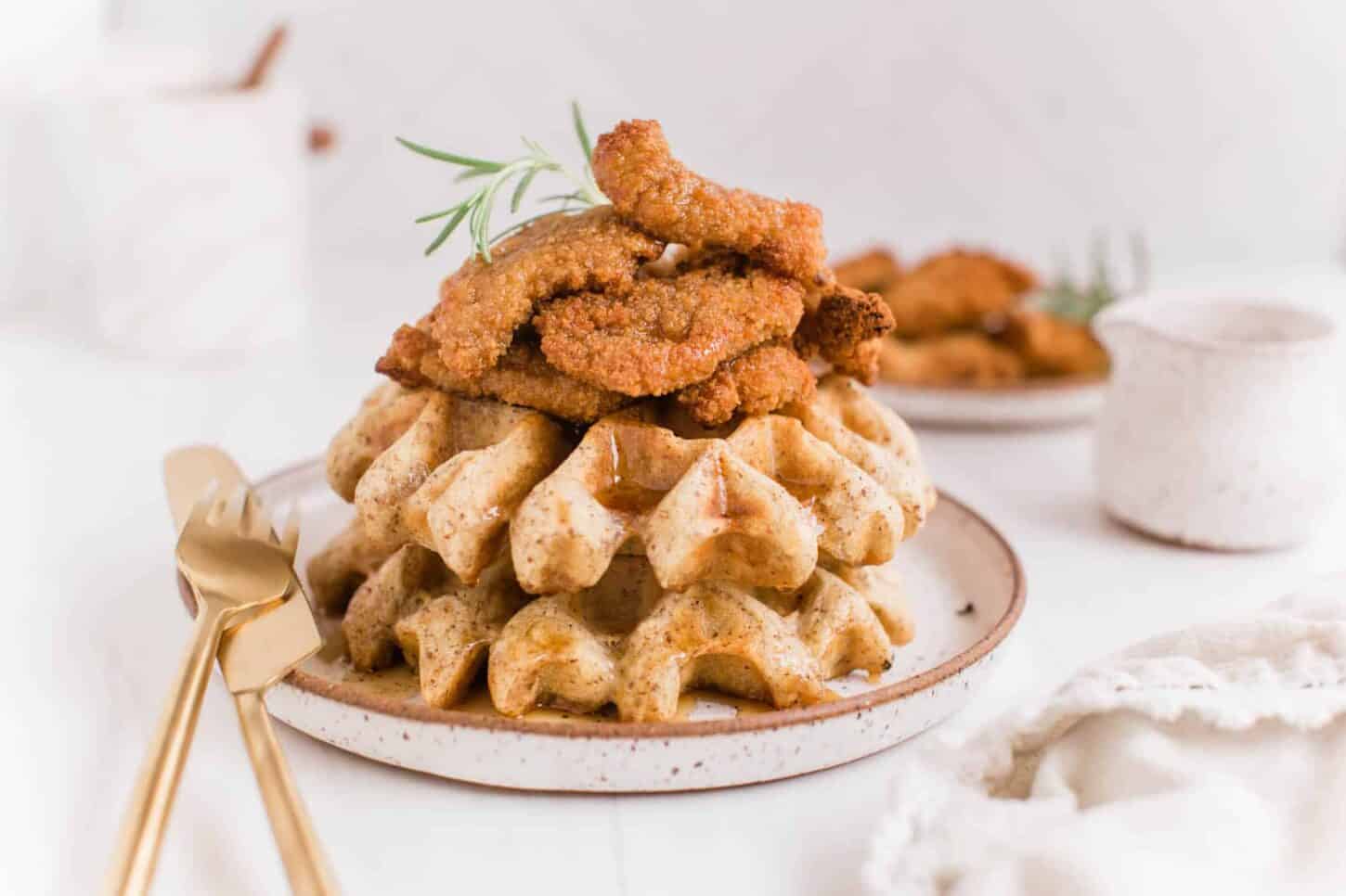 Vegan Chicken and Waffles Recipe Stacked on a Rustic Plate With Gold Cutlery