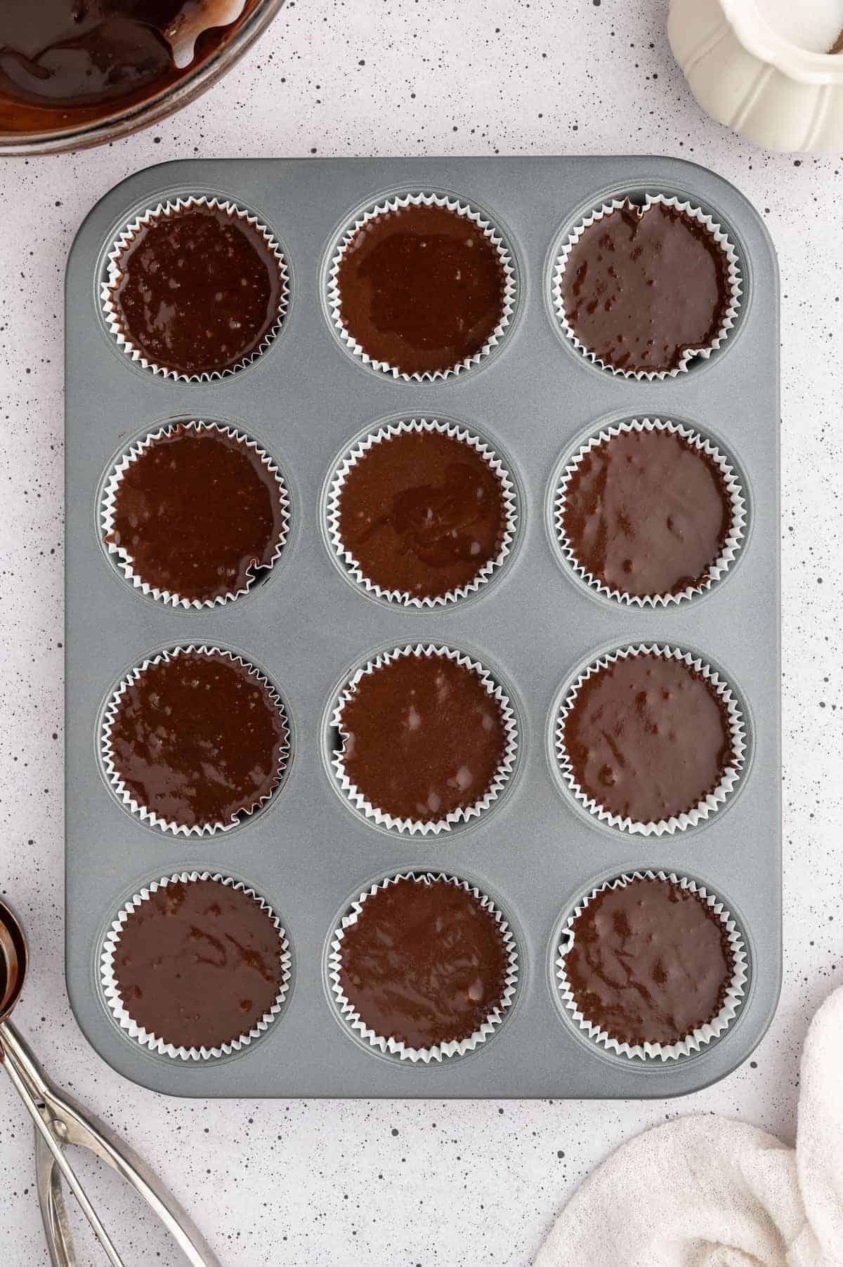 Vegan chocolate cupcake batter divided evenly into liners in a cupcake pan.