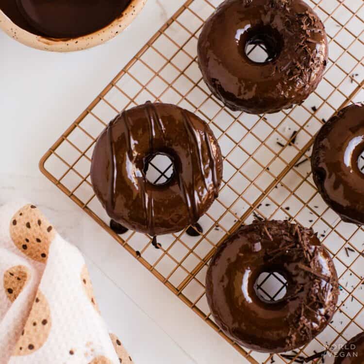 Vegan chocolate donuts with chocolate icing cooling on a baking rack.