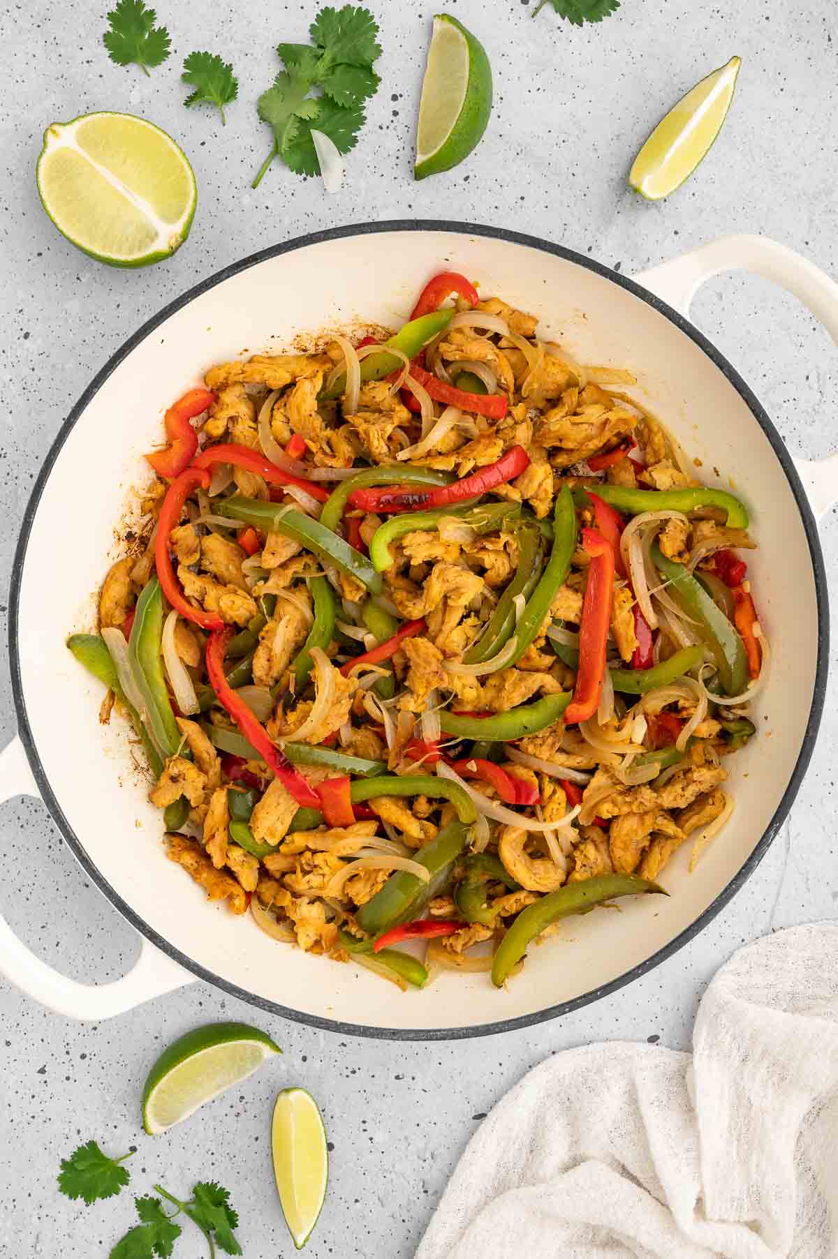 Vegan fajita filling in a pan surrounded with lime wedges.