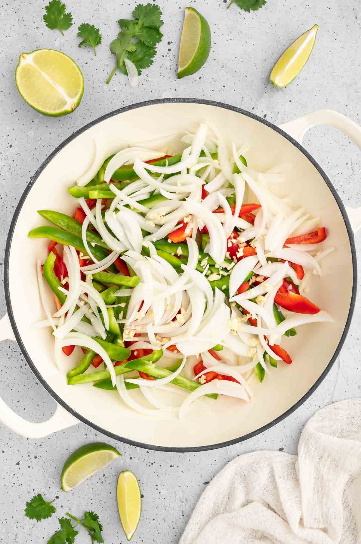 Sliced onions and peppers in a skillet.