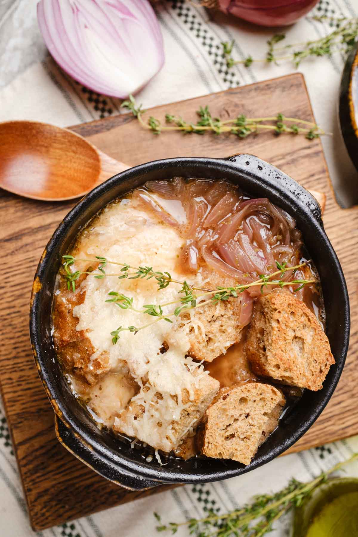 Vegan French Onion Soup in a bowl topped with vegan cheese and sprigs of thyme.