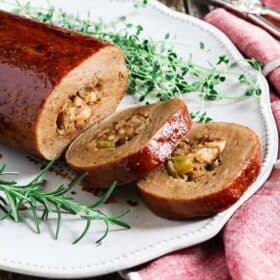 vegan holiday roast on a plate with green herb garnish