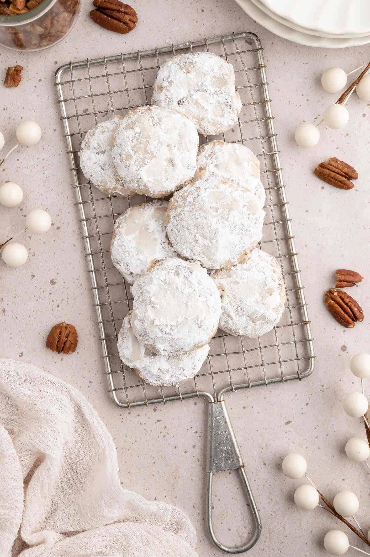 Mexican wedding cookies stacked on a drying rack.